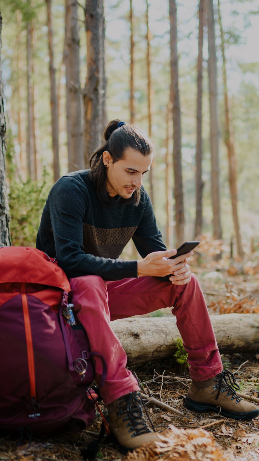 Young caucasian man using a smart phone in the nature.  Using technology in the nature concept.