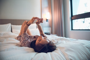Young Beautiful Woman Using Smart Phone On Bed