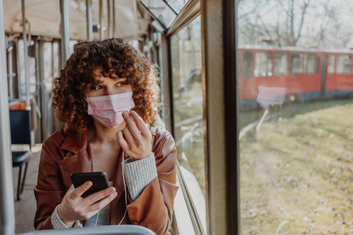 Young woman in public transportation during the pandemic. Safety apps for women for iPhone and Andro...