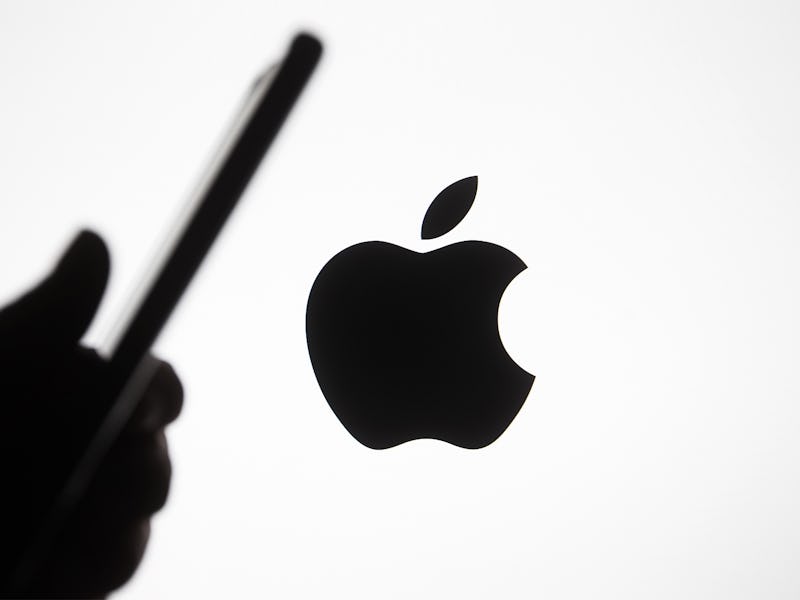 The logo for Apple appears in the background in black color. The rest of the background is white. A ...