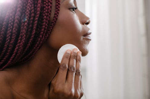 Beautiful African woman cleaning her face with cotton pad.