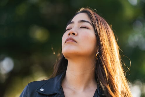 A portrait of a young woman relaxing with her eyes closed in nature.