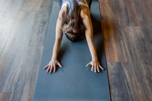 Young woman stretching her back while doing yoga at the gym. Here's why your muscles hurt when you'r...