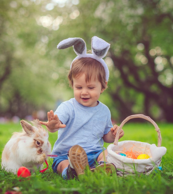 Happy child playing with bunny on Easter egg hunt in springtime, wondering 'is the easter bunny real...