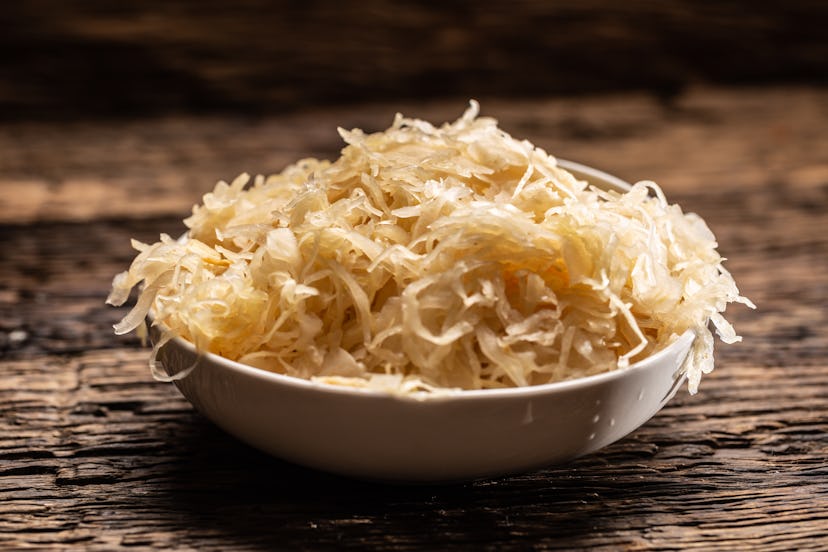 A bowl full of raw sauerkraut cabbage pickle on a rustic dark surface.