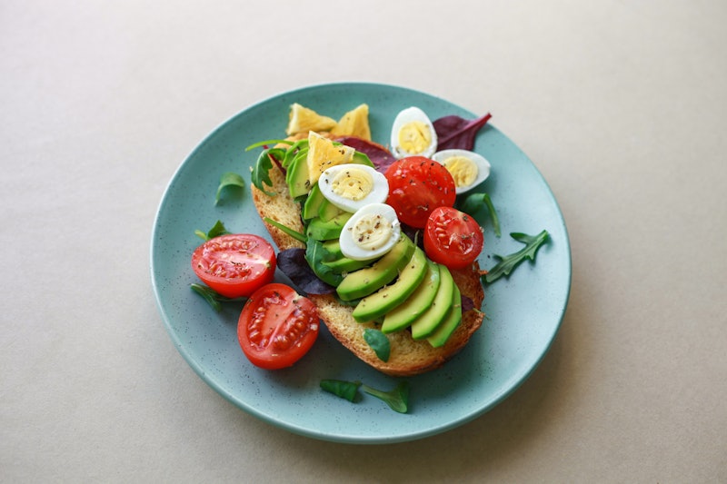 Toast sandwich with avocado, egg and tomato in plate on the table. Concept of healthy vegetarian org...