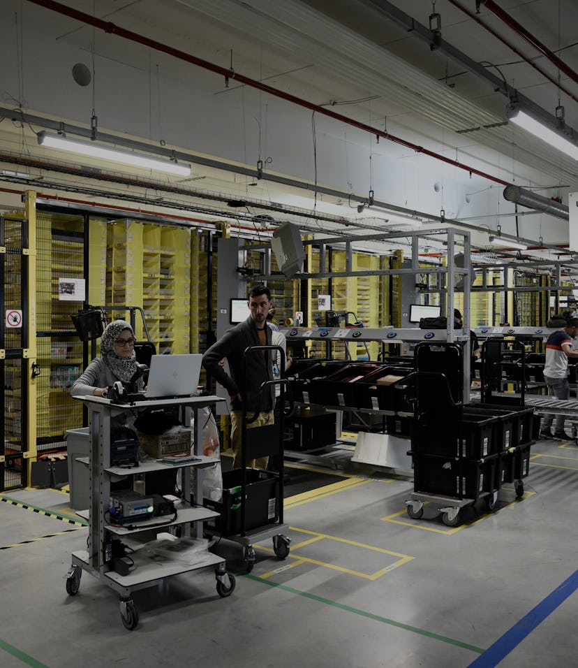 Employees are seen on duty at work stations part of mobile robotic fulfilment systems also known as ...