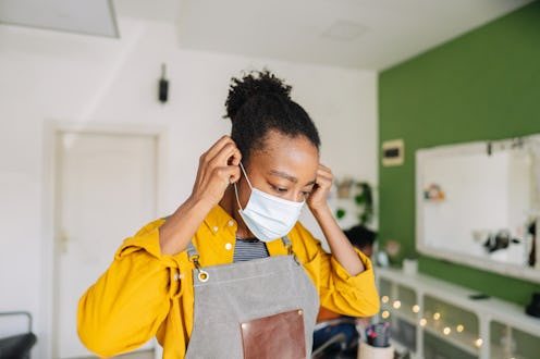 Portrait of a young African American hairdresser, proud owner of a small business, wearing protectiv...