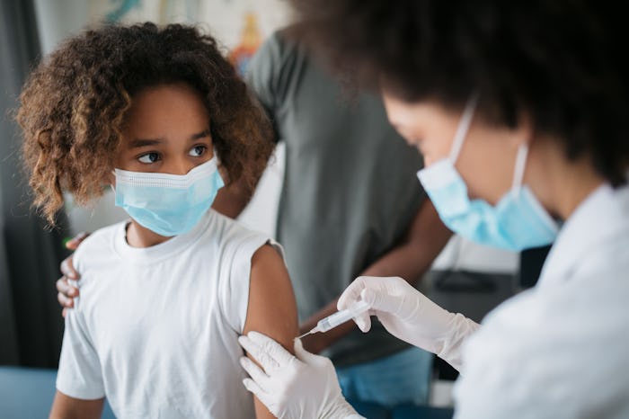 Close up of a little African American girl taken to a medical clinic by her father and being given t...