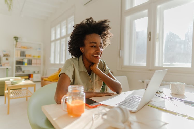 Photo of a young woman finishing up some work on her laptop from her home-based office; a millennial...