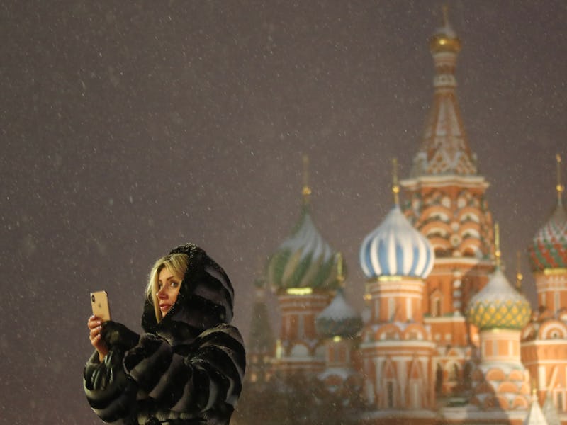 MOSCOW, RUSSIA - FEBRUARY 4, 2021: A woman stands in front of St Basil's Cathedral during a snowfall...