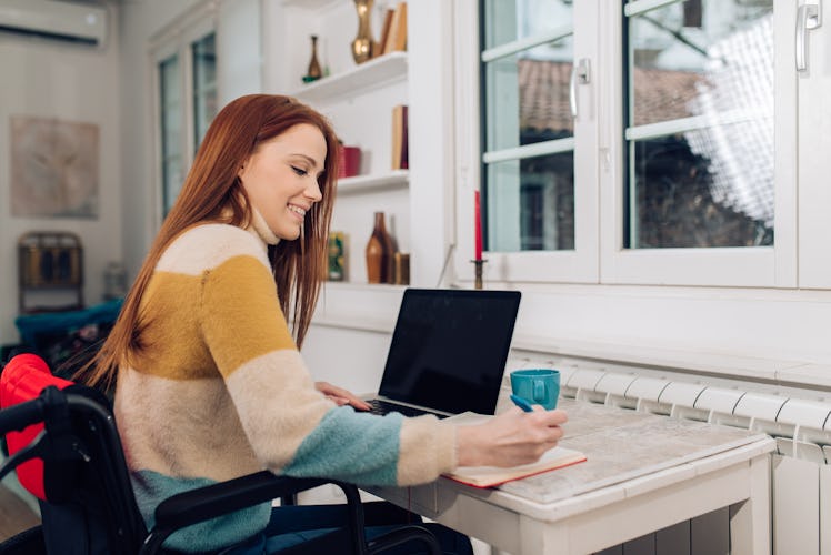 Young redhead woman in a wheelchair working online from home.