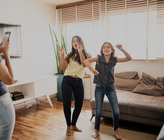 Mother filming teenager daughters dancing at home