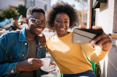 Happy smiling African American couple, sitting in a coffee shop, relaxing and enjoying their vacatio...