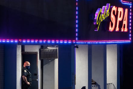 A police officer stands outside a massage parlor where three people were shot and killed on March 16...