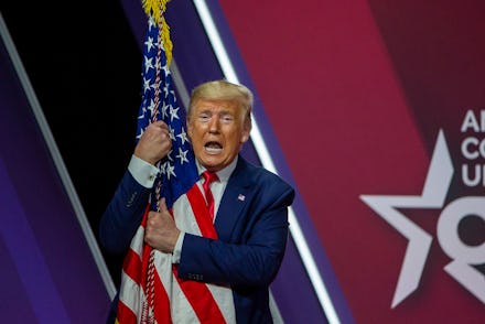 NATIONAL HARBOR, MARYLAND - FEBRUARY 29: President Donald Trump hugs the flag of the United States o...