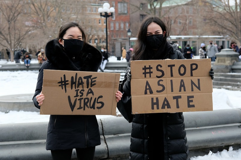 NEW YORK, NEW YORK - FEBRUARY 20: Protestors hold signs that read "hate is a virus" and "stop Asian ...