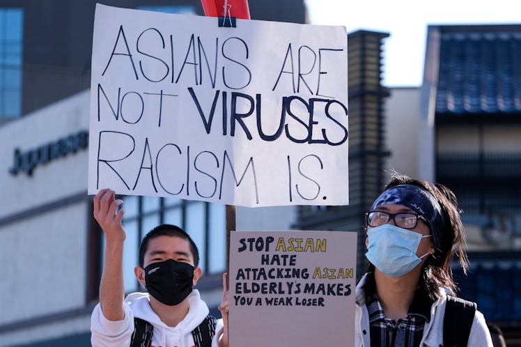 Demonstrators wearing face masks and holding signs take part in a rally "Love Our Communities: Build...