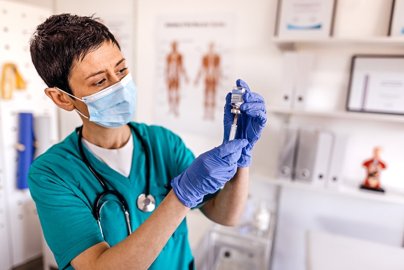 A medical professional prepares a syringe for vaccination. The underlying conditions that qualify pe...