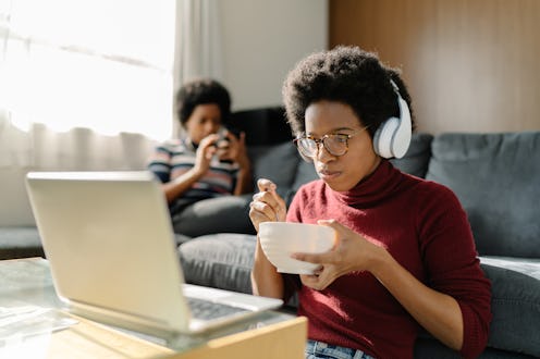 Two Black women are spending their time using a laptop and a smart phone comfortably at home.