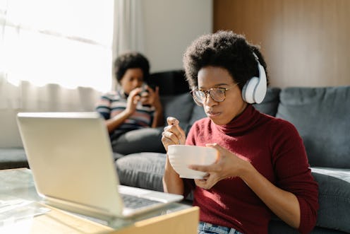 Two Black women are spending their time using a laptop and a smart phone comfortably at home.