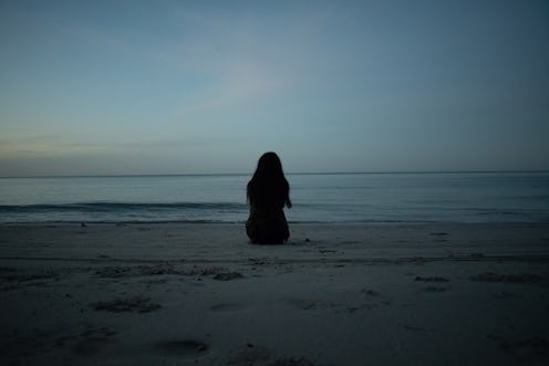 A woman sits and looks at the sunrise. Trauma can cause deep damage to the brain.