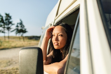 Photo of young woman on a summer road trip with a van vehicle