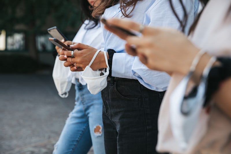 Three people stand outside in a line, all texting on their phones. Figuring out what texts to send a...