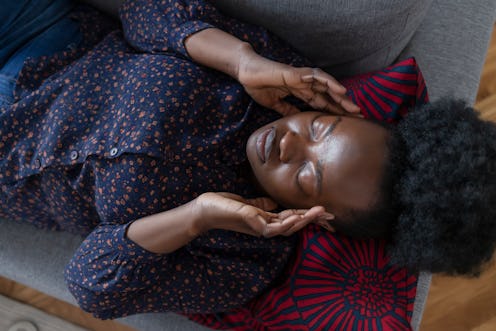 A woman lies on a couch with an allergy-induced headache.