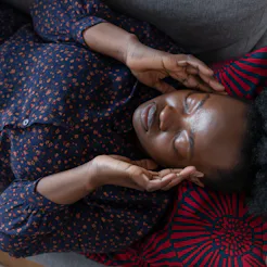 A woman lies on a couch with an allergy-induced headache.