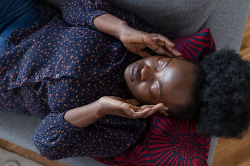 A woman lies on a couch with an allergy-induced headache.