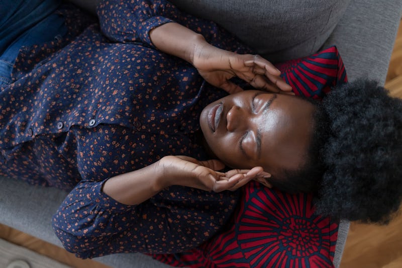 A woman lies on a couch with an allergy-induced headache.