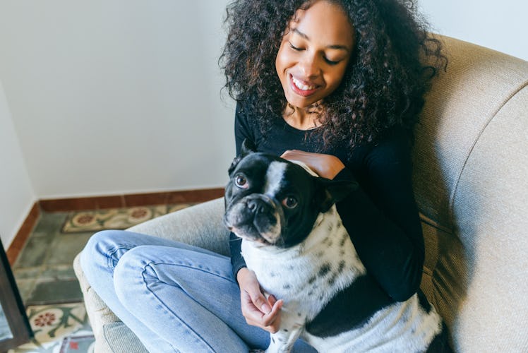 A young woman sits with her dog and waits for a dog subscription box to arrive.