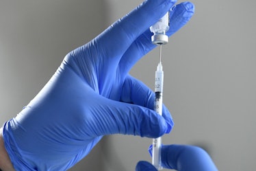 An image of a hand with a syringe pulling out some medicine