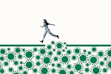 Full length side view of happy young woman jumping over large green coronavirus under ramp against w...