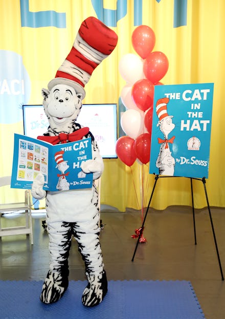 Dr. Seuss mascot holding "The Cat in the Hat" book with a banner and balloons in the background