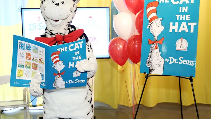 Dr. Seuss mascot holding "The Cat in the Hat" book with a banner and balloons in the background