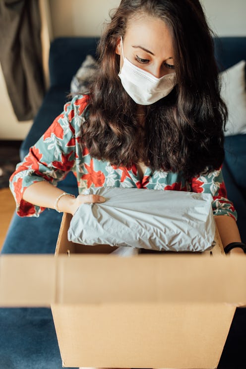 A woman wearing a mask packs a banker's box. What happened when 5 roommates got sick with COVID the ...