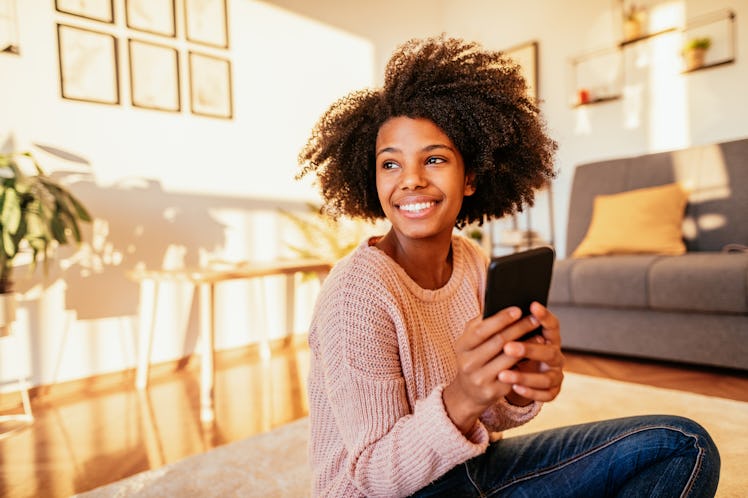Young African American woman at home, dressed in casual sweater and working or studying.