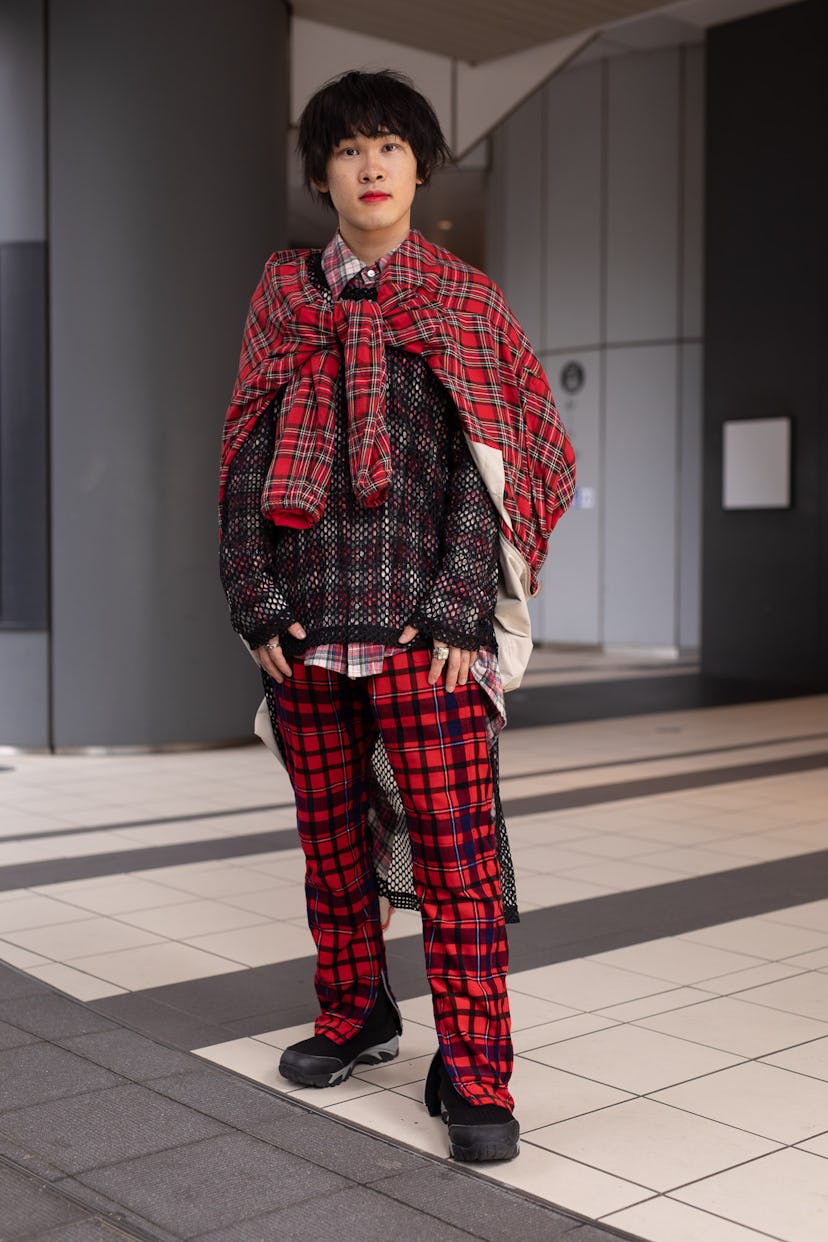 TOKYO, JAPAN - MARCH 20: A guest is seen on the street wearing a red plaid tied jacked, fishnet shir...