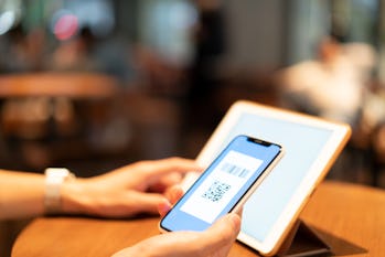 Asian man holding mobile payment code in shop