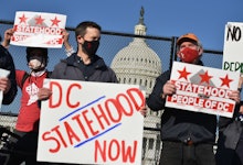 Activists hold signs as they take part in a rally in support of DC statehood near the US Capitol in ...