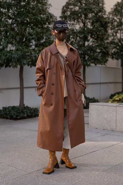 TOKYO, JAPAN - MARCH 15: A guest is seen on the street wearing brown leather coat, black cap, brown leather face mask, brown shoes during the Rakuten Fashion Week Tokyo 2021 autumn/winter on March 15, 2021 in Tokyo, Japan. (Photo by Matthew Sperzel/Getty Images)