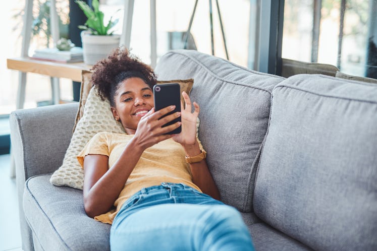 Shot of a young woman using a smartphone on the sofa at home