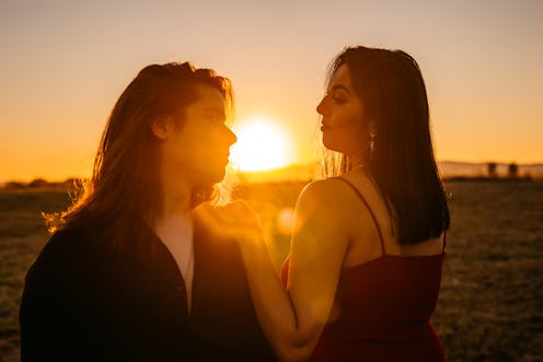Young beautiful heterosexual couple together at sunset face to face.