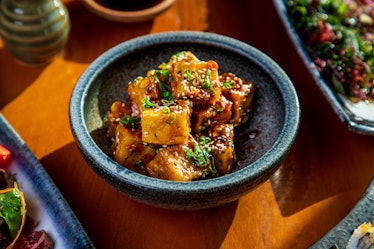 Tofu cubes serving in a bowl, seasoned with black and white sesame and chopped scallion