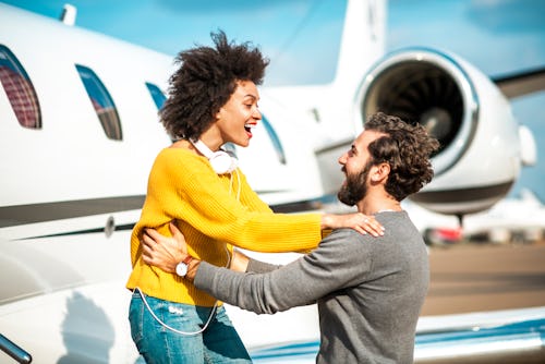 A woman and man embrace outside of an airplane. Taurus and Leo zodiac compatibility
