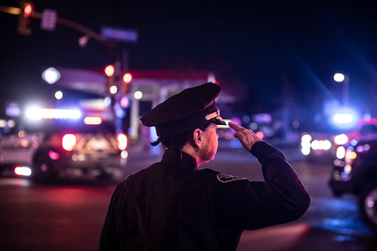 A police officer salutes as a procession carrying the body of a fellow officer leaves King Sooper's ...