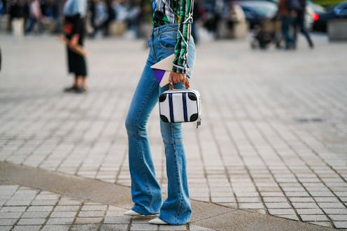 PARIS, FRANCE - OCTOBER 01: A guest wears blue flare denim pants, a black and white bag, outside Lou...