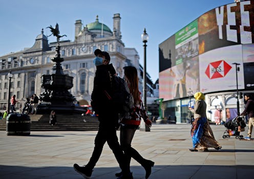 A pedestrian wearing a face covering due to Covid-19 through an almost deserted Piccadilly Circus in...